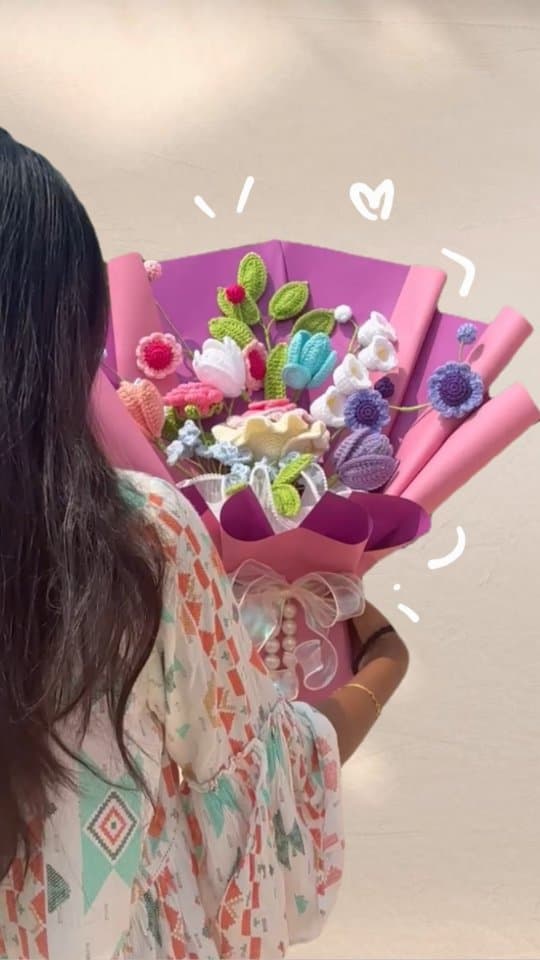 Person holding a magenta crochet bouquet